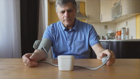 An aged man measuring the blood pressure at home