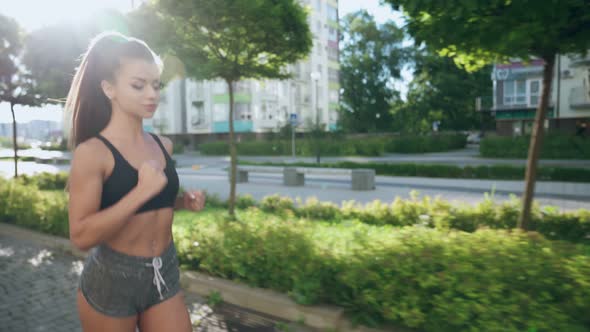 Muscular Woman Running in Morning City Streets