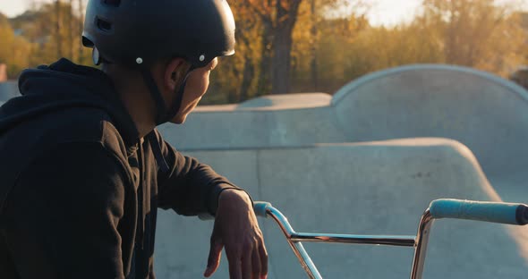 A Cyclist Sits on a Ramp in a Park on a Spring Afternoon with a