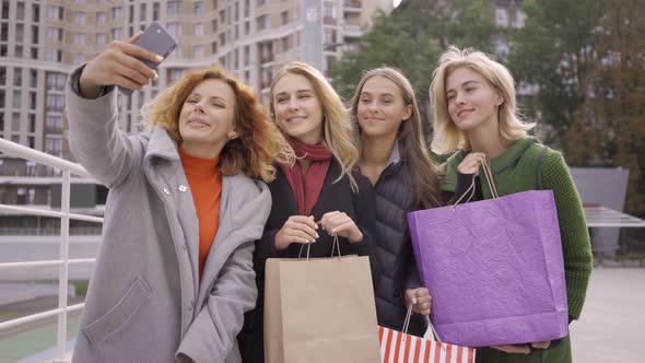 Four Happy Friends with Shopping Bags and Taking Selfie. Four Fashion Women in the City. Leisure