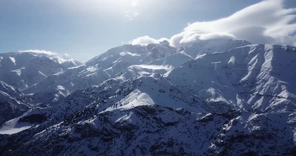 Fly over snow covered mountain and highland villages in Alamut valley in Iran sunny day with plenty