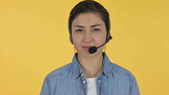 Indian Woman with Headset Looking at Camera, Yellow Background 