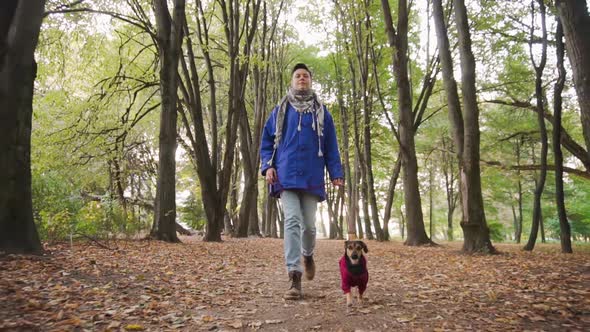 Woman walking with a dog in a park, slow motion.