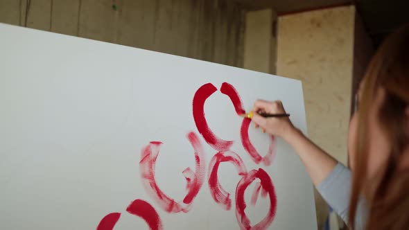 Closeup of Unrecognizable Female Artist Paints Red Peonies or Other Flowers with Brush on the Canvas