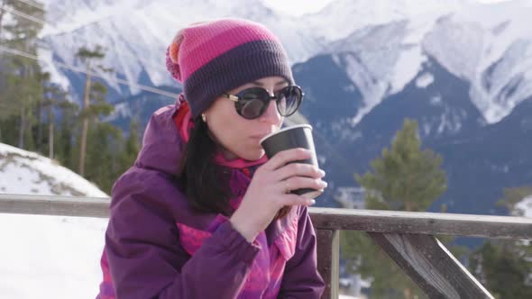 Woman Drinking Warm Tea in the Rustic Wooden Terrace on Mountain. Girl Is Enjoying the Panoramic