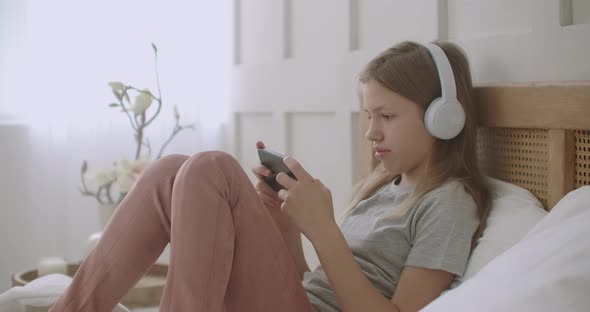 Preteen Girl Is Using App for Communicating on Smartphone, Talking and Listening By Headphones