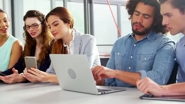 Business executives using laptop, mobile phone and digital tablet in meeting