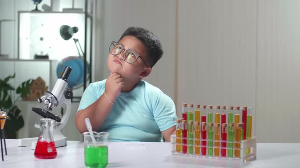 Cute Little Scientist Looking At Liquid In Test Tube And Thinking