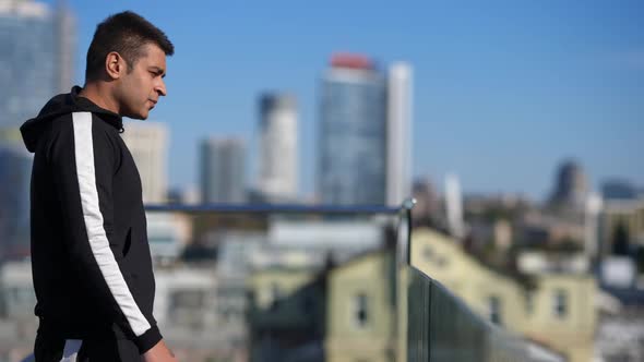 Side View Middle Eastern Man Walking in Slow Motion to Glass Fence on Rooftop Admiring Sunny Summer