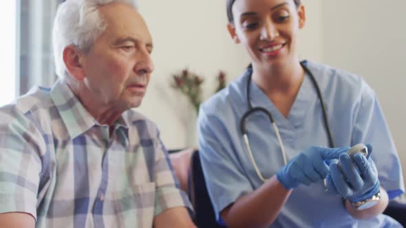 Video of happy biracial female doctor checking glucose level to caucasian senior man