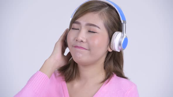 Face of Young Happy Asian Woman Thinking While Listening To Music