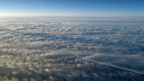 Incredible view from the cockpit of an airplane flying high above the clouds leaving a long white co