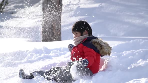 Cute Asian Child Wearing Winter Clothes Playing On Snow In The Park