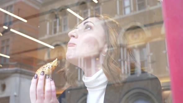 Slow motion shot of young woman eating croissant in a cafe