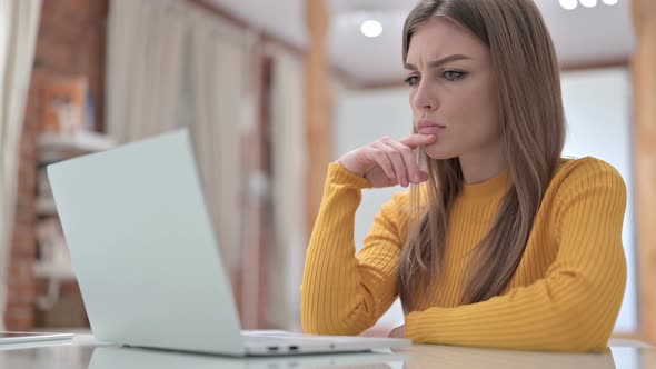 Beautiful Young Woman Thinking and Working on Laptop