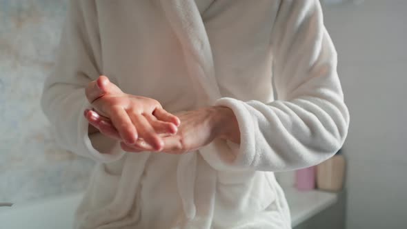 Unrecognizable woman in bathrobe applying moisturizing cream on hands. Shot with RED helium camera i