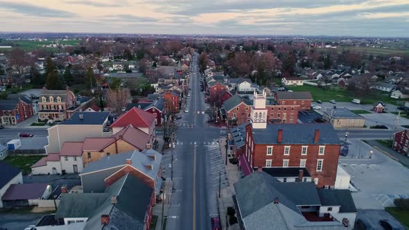 Aerial Pullback View of a Small Town and a Steeple as the Sunrises Behind the Camera and Breaks the