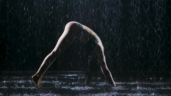 Upward Downward Dog Yoga Position Performed By a Slender Woman Surrounded By Raindrops. The Sexy