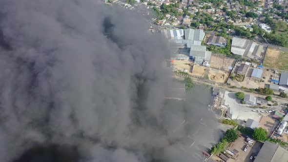 Drone flying through big column of rising smoke of building fire. Aerial shot