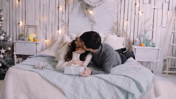 Happy Young Couple Having Fun on a Comfortable Bed, Enjoying the Christmas Holidays Together.