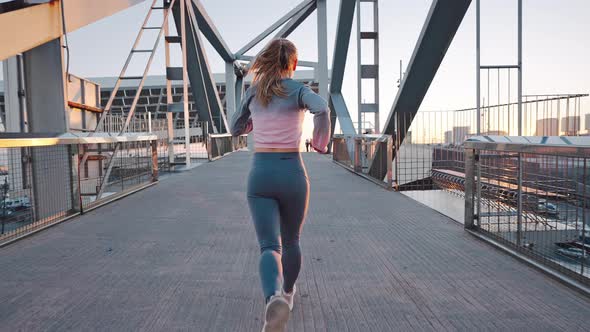 Rear View Active Woman Jogger Running Forward Modern Metal Bridge