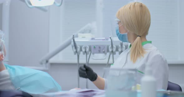 Dentist Takes a Drill From the Dental Unit and Begins to Drill a Tooth the Process of Caries