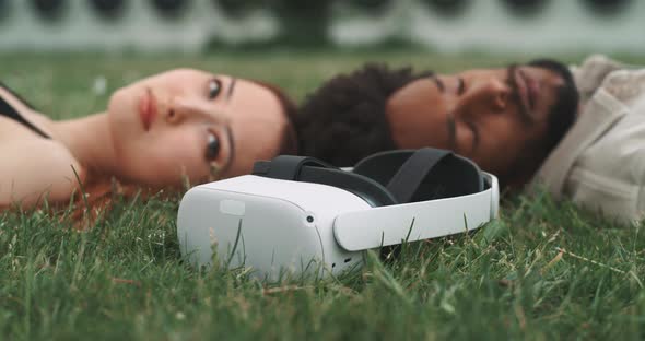 A young couple lying on the ground with virtual reality goggles