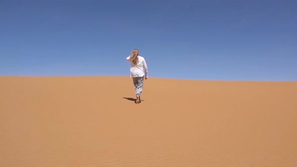 Blond Woman Walks Along Sahara Desert