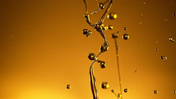 Super Slow Motion Shot of Splashing Oil on Golden Background at 1000Fps