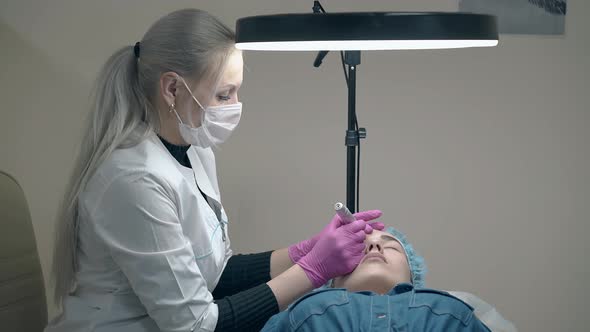 Cosmetician Applies Eyebrow Makeup Under Black Round Lamp