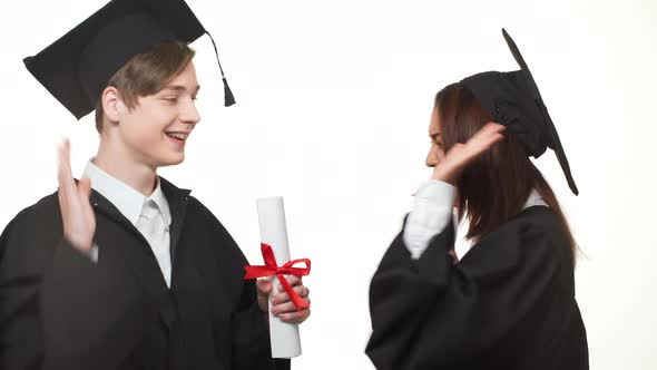 African American Graduate Female Rejoicing with Caucasian Young Male in Black Robe Who Throwing in