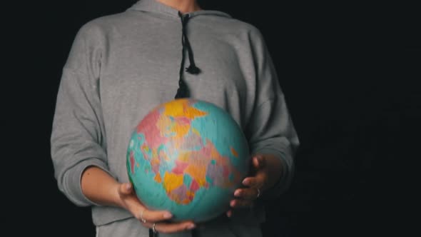 Girl's Hands Toss a Geographic Globe in Slowmo