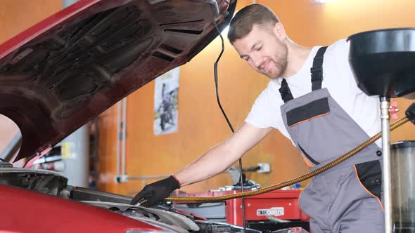 A Mechanic Man Makes an Oil Change in a Car