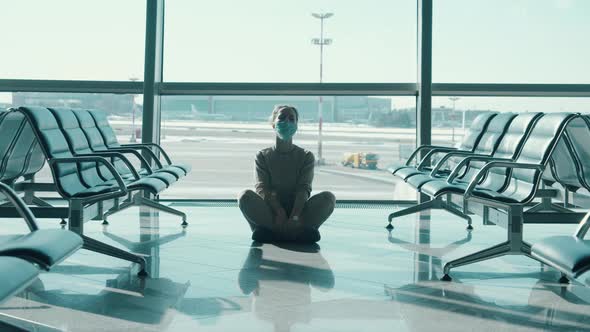 A Lady in a Face Mask Starts Meditating at the Airport