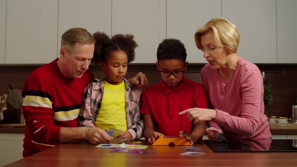 Excited Multiethnic Grandchildren with Grandparents Playing Color Puzzle Indoors