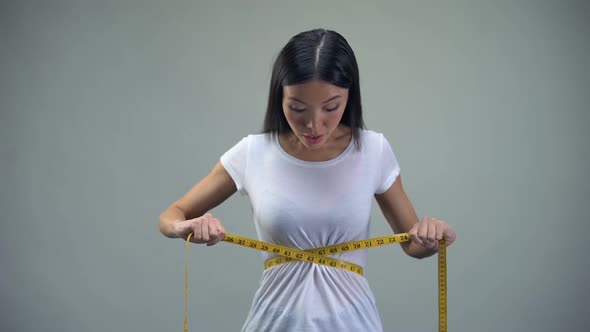 Asian Woman Measuring Her Waist, Satisfied With Training and Diet Results, Fit