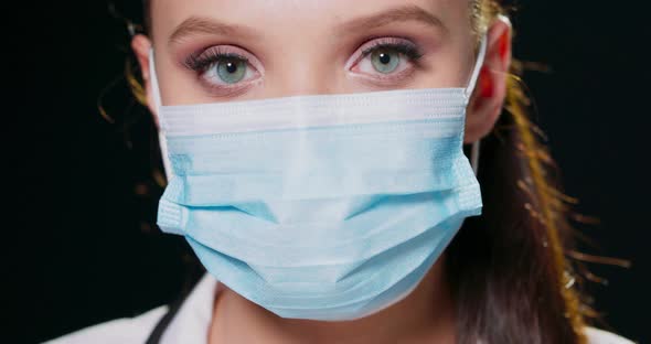 Closeup Face of a Woman Wearing a Protective Medical Face Mask Looking at the Camera Head Portrait