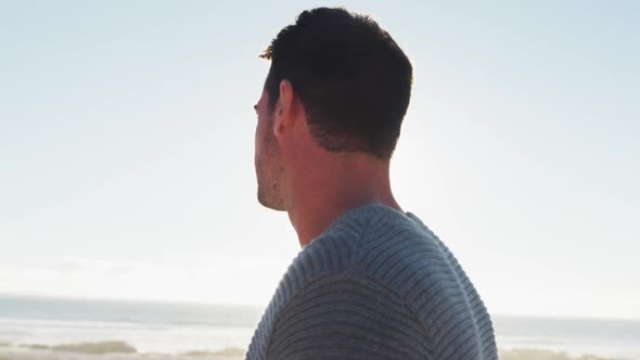 Happy caucasian man standing and smiling by the sea