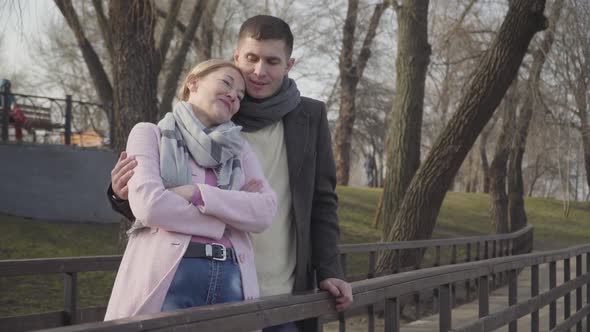 Laughing Young Man Hugging Older Cheerful Woman in Park. Portrait of Happy Loving Caucasian Couple