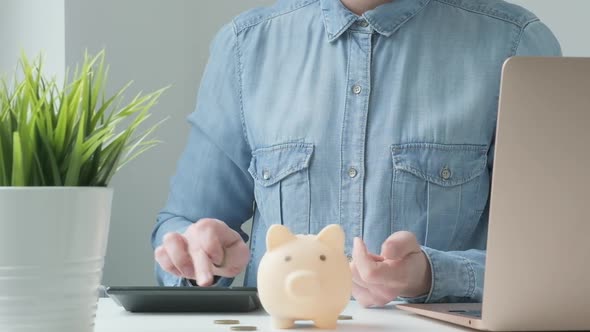 Woman Putting Coins in Piggy Bank