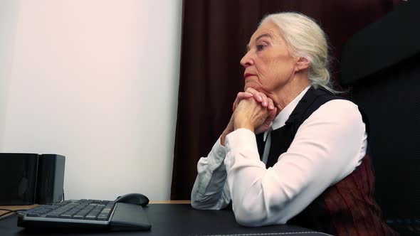 Old Unhappy Caucasian Woman Looks at Computer in Home and She Doesn't Know