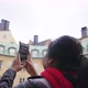 Asian woman standing and taking a picture of yellow big building in Sweden - VideoHive Item for Sale