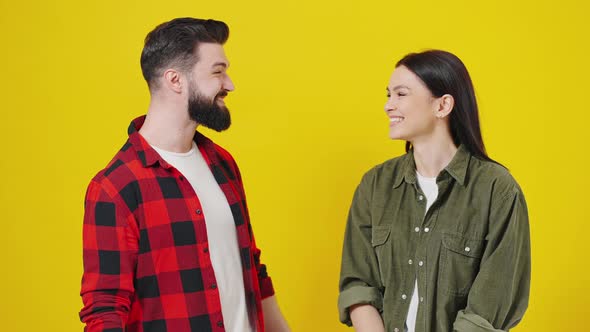 Beautiful Young Couple Together Standing Over Yellow Background Pointing with Finger to the Camera