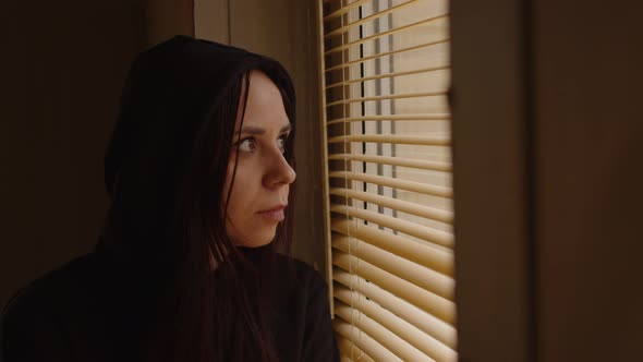 Close Up of Young Woman Watching Through Window Blinds at Home