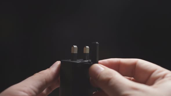 Close-up of a Man's Hand on a Dark Background Holding a Power Supply