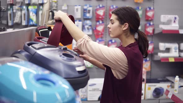 Girl Choosing Vacuum Cleaner in Appliance Store