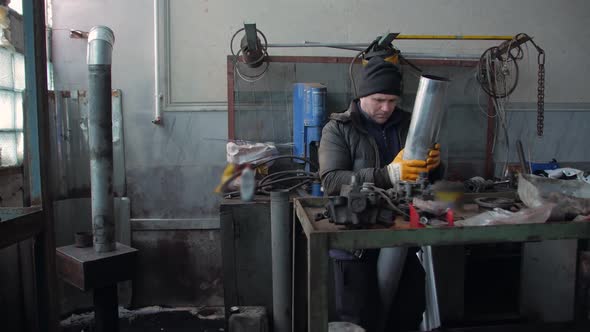 Worker In A Workshop With A Pipe