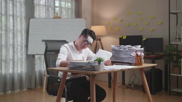 Sick Asian Man Working Hard With Documents At The Office