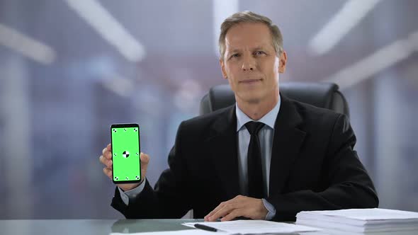 Joyful Male Boss in Suit Showing Green Screen Smartphone at Camera, Business App