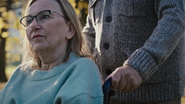 Close up of senior man pushing woman on wheelchair in park. Shot with RED helium camera in 8K